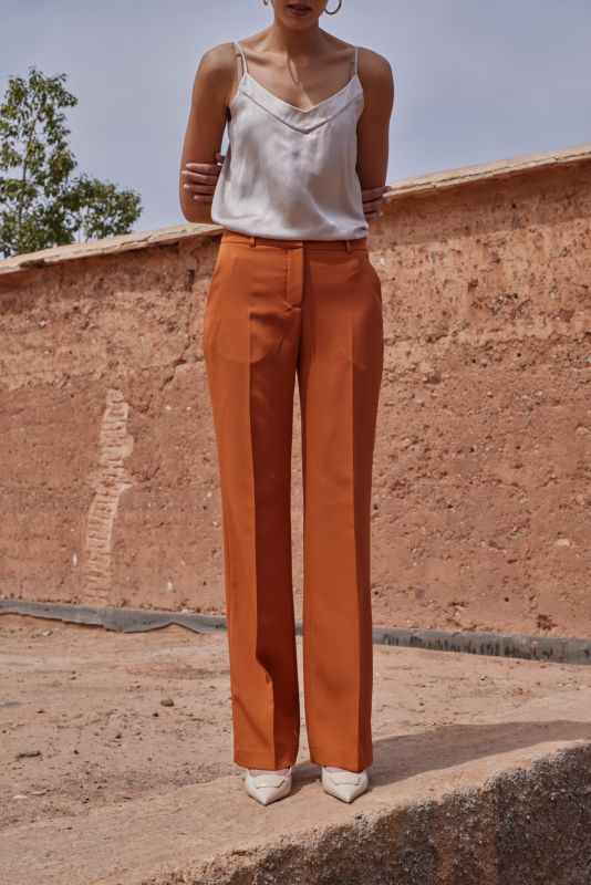 Gros plan sur une femme en PANTALON ROSARIO whisky et top en satin blanc, soulignant la coupe parfaite et l'élégance du tissu.