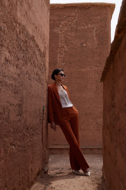 Gros plan sur une femme en PANTALON ROSARIO whisky et top en satin blanc, soulignant la coupe parfaite et l'élégance du tissu.