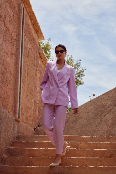 Femme portant le pantalon Teresa lilas avec un blazer assorti, descendant des escaliers en extérieur.