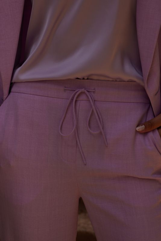 Gros plan sur le pantalon Teresa lilas, montrant la ceinture à nouer et le haut en soie.
