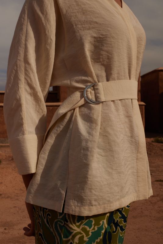 Gros plan de la blouse Amanda beige avec une ceinture, montrant les détails du tissu et la boucle.